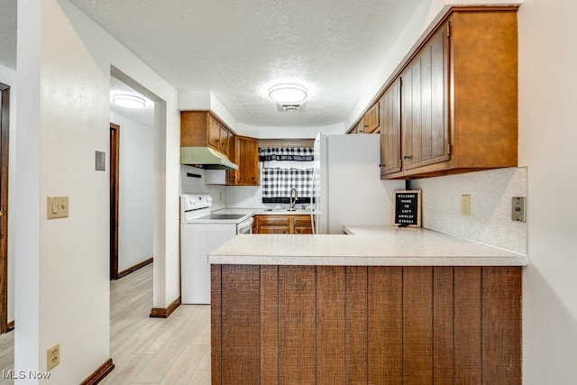 2377 Ansley St, Alliance, OH 44601 - kitchen featuring under cabinet range hood, white appliances, decorative backsplash, a peninsula, and a textured ceiling