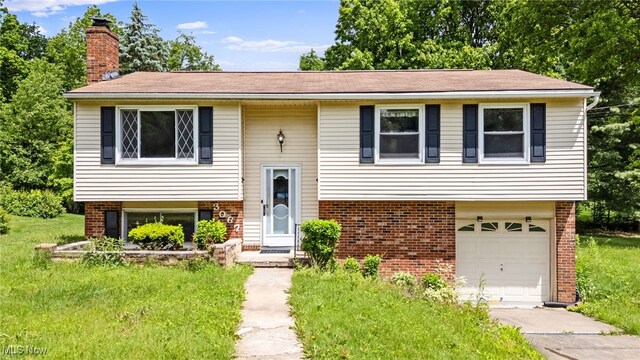 3067 Bronco Dr, Clinton, OH 44216 - bi-level home with brick siding, a chimney, a garage, and driveway