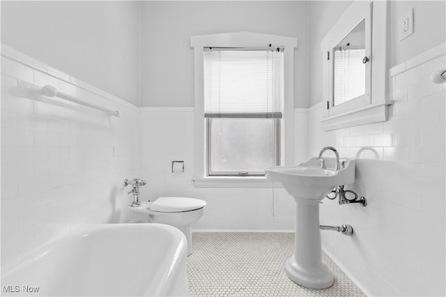 2472 Overlook Rd Unit 11, Cleveland Heights, OH 44106 - bathroom with a bath, toilet, healthy amount of natural light, a wainscoted wall, and tile walls