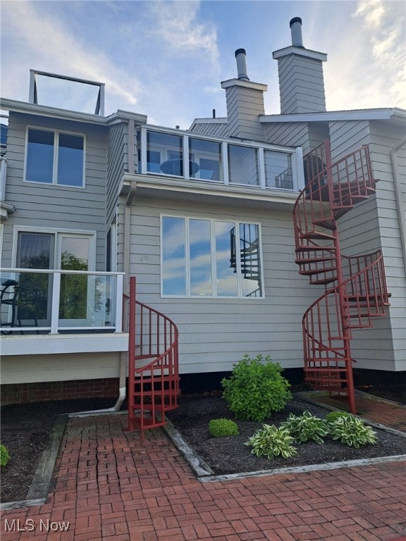 629 Main St, Vermilion, OH 44089 - rear view of house featuring stairway and a chimney