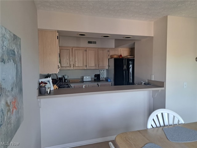 629 Main St, Vermilion, OH 44089 - kitchen featuring freestanding refrigerator, light brown cabinetry, a textured ceiling, and a peninsula