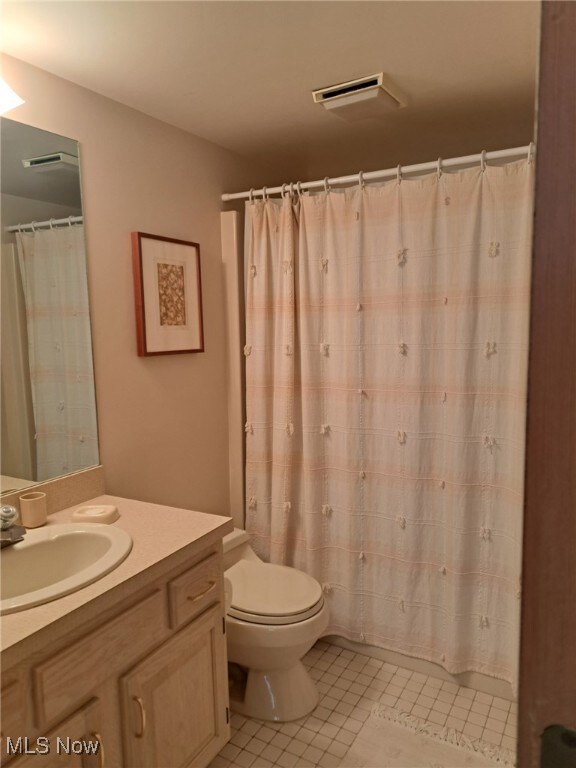 629 Main St, Vermilion, OH 44089 - bathroom featuring toilet, vanity, tile patterned flooring, and curtained shower
