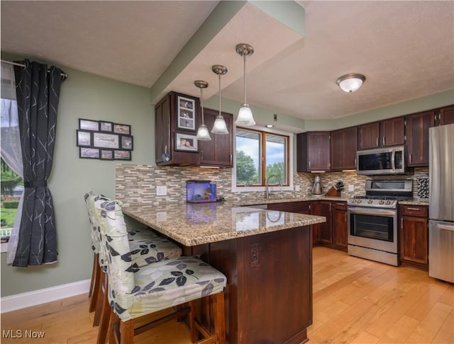 4184 Meadowview Dr NW, Canton, OH 44718 - kitchen featuring appliances with stainless steel finishes, a peninsula, light wood-style flooring, and plenty of natural light
