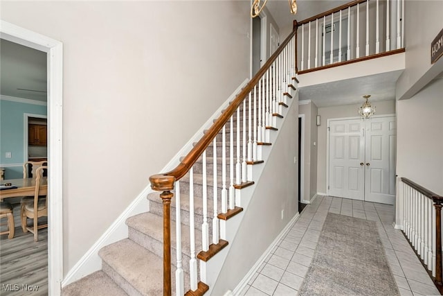 12115 Fowlers Mill Rd, Chardon, OH 44024 - stairs featuring tile patterned flooring, a chandelier, baseboards, ornamental molding, and a high ceiling