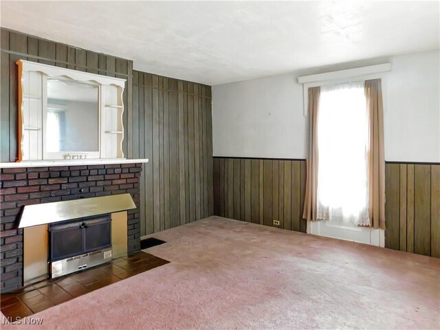 192 Walnut St, Geneva, OH 44041 - unfurnished living room with wooden walls, healthy amount of natural light, wainscoting, a fireplace, and carpet