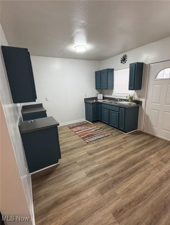 666 Parkwood Rd, Cleveland, OH 44108 - kitchen featuring dark countertops, wood finished floors, healthy amount of natural light, and blue cabinets