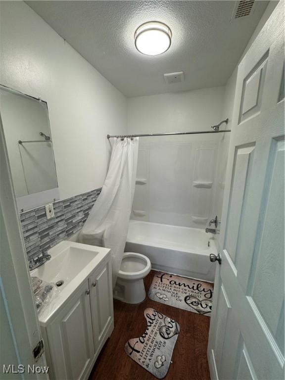 666 Parkwood Rd, Cleveland, OH 44108 - bathroom with shower / tub combo with curtain, a textured ceiling, vanity, toilet, and wood finished floors