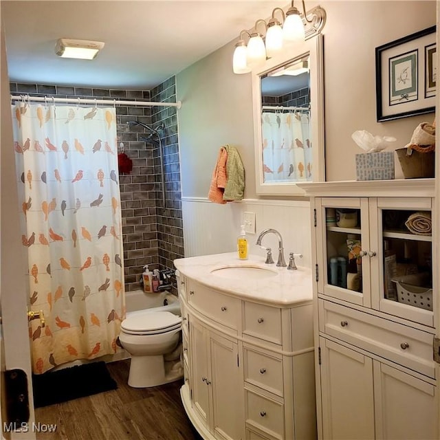 13423 Price St NE, Alliance, OH 44601 - bathroom with vanity, toilet, wood finished floors, shower / bathtub combination with curtain, and a wainscoted wall