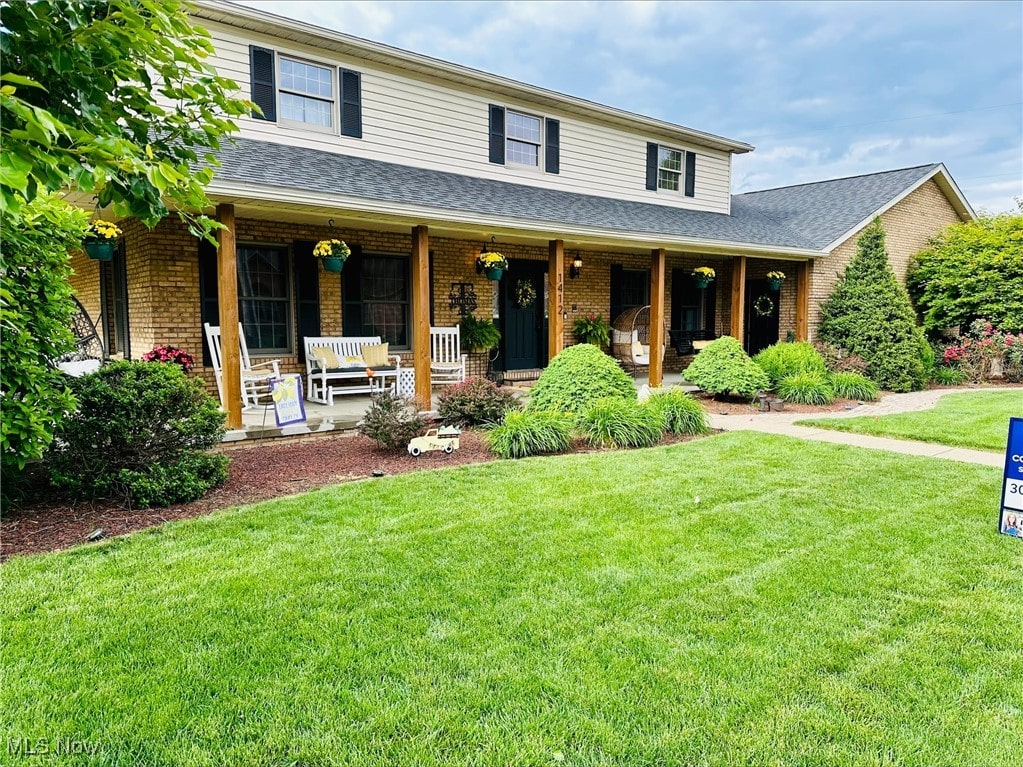 1412 Boulevard Dr, Belpre, OH 45714 - view of front facade with brick siding, a porch, roof with shingles, and a front yard