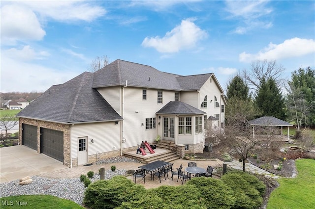 1014 Kings Ridge Blvd, Wadsworth, OH 44281 - rear view of house featuring an attached garage, a shingled roof, concrete driveway, and a patio