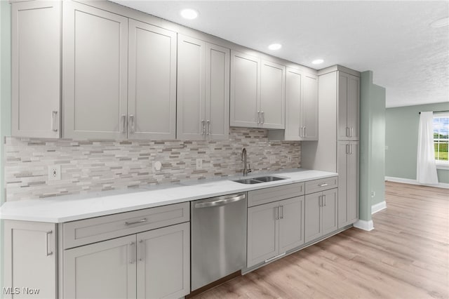 6937 Reynolds Rd, Mentor, OH 44060 - kitchen featuring stainless steel dishwasher, a sink, baseboards, light wood-style flooring, and tasteful backsplash
