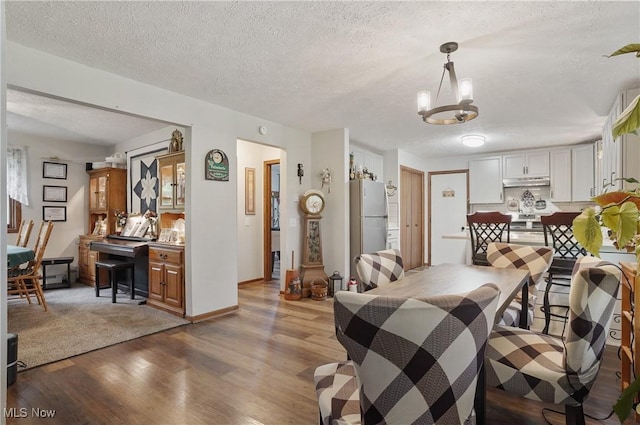 22010 Mountz Rd, Minerva, OH 44657 - dining space featuring light wood finished floors, a textured ceiling, a chandelier, and baseboards