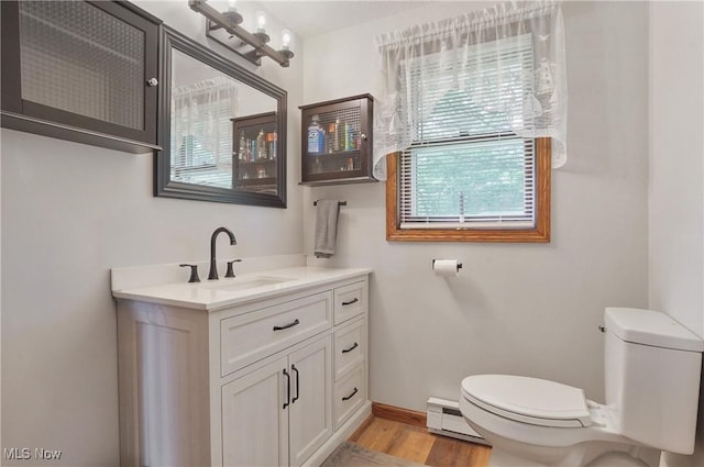 22010 Mountz Rd, Minerva, OH 44657 - half bathroom featuring toilet, a baseboard heating unit, vanity, wood finished floors, and baseboards