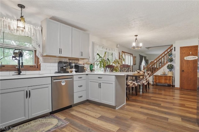 22010 Mountz Rd, Minerva, OH 44657 - kitchen featuring a chandelier, stainless steel dishwasher, a textured ceiling, a peninsula, and wood finished floors