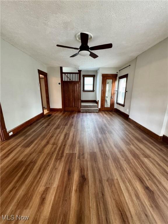 1131 16th St NW, Canton, OH 44703 - unfurnished living room featuring dark wood-style flooring, a textured ceiling, baseboards, and ceiling fan