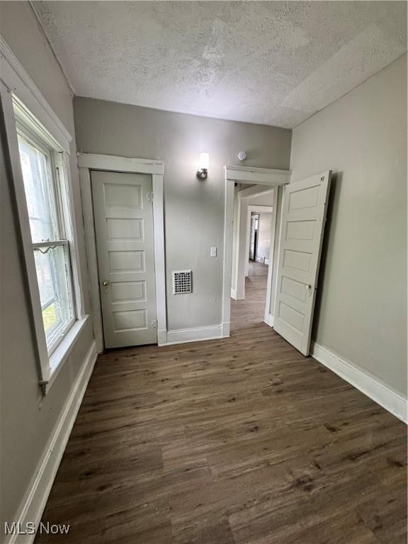 483 E 128th St, Cleveland, OH 44108 - spare room with a textured ceiling, baseboards, dark wood finished floors, and plenty of natural light