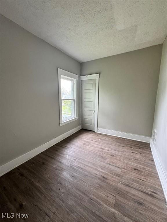 483 E 128th St, Cleveland, OH 44108 - unfurnished bedroom featuring baseboards, wood finished floors, and a textured ceiling