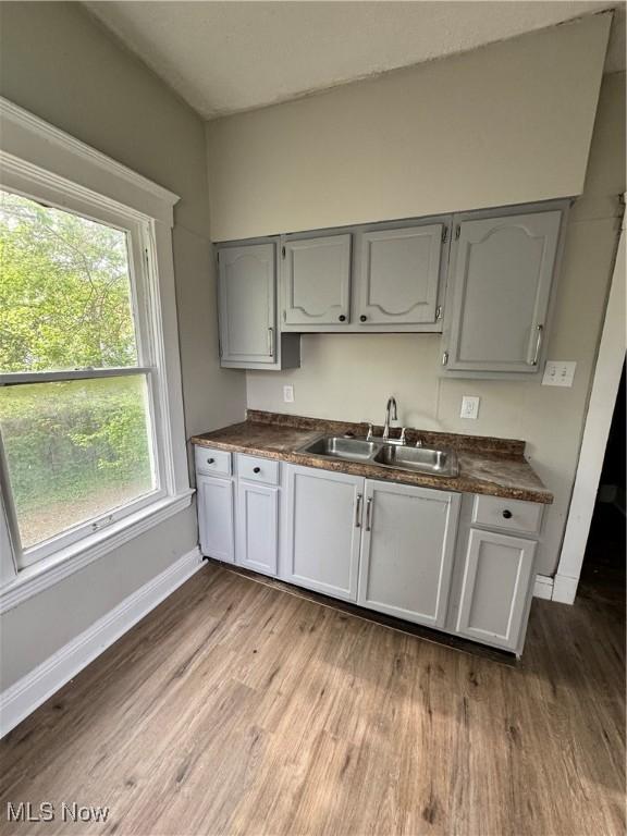 483 E 128th St, Cleveland, OH 44108 - kitchen with a sink, baseboards, dark countertops, dark wood-style flooring, and gray cabinetry