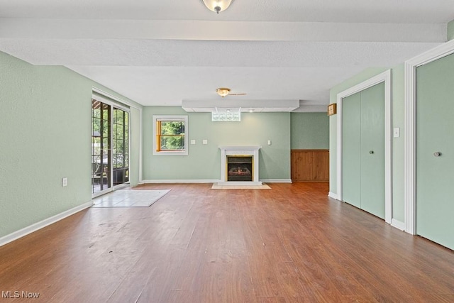 153 Cheyenne Trl, Malvern, OH 44644 - unfurnished living room featuring wood finished floors, a fireplace with raised hearth, wainscoting, and baseboards