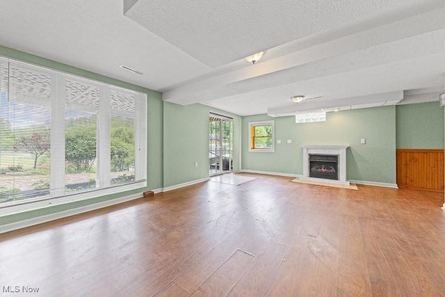 153 Cheyenne Trl, Malvern, OH 44644 - unfurnished living room featuring wood finished floors, a fireplace, a textured ceiling, a wainscoted wall, and baseboards