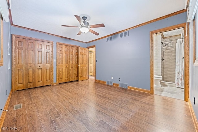 153 Cheyenne Trl, Malvern, OH 44644 - unfurnished bedroom with two closets, wood finished floors, baseboards, and crown molding