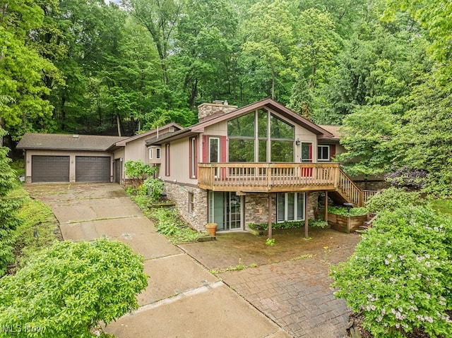153 Cheyenne Trl, Malvern, OH 44644 - view of front of home featuring stone siding, a wooden deck, concrete driveway, a chimney, and stairway