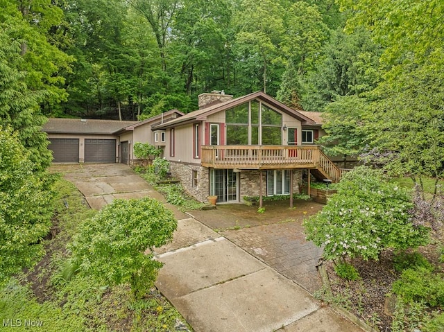 153 Cheyenne Trl, Malvern, OH 44644 - view of front of home with stone siding, a chimney, a deck, a garage, and concrete driveway
