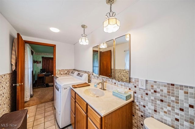 1092 State Route 46 N, Jefferson, OH 44047 - laundry room featuring washing machine and dryer, tile walls, light tile patterned floors, and a wainscoted wall