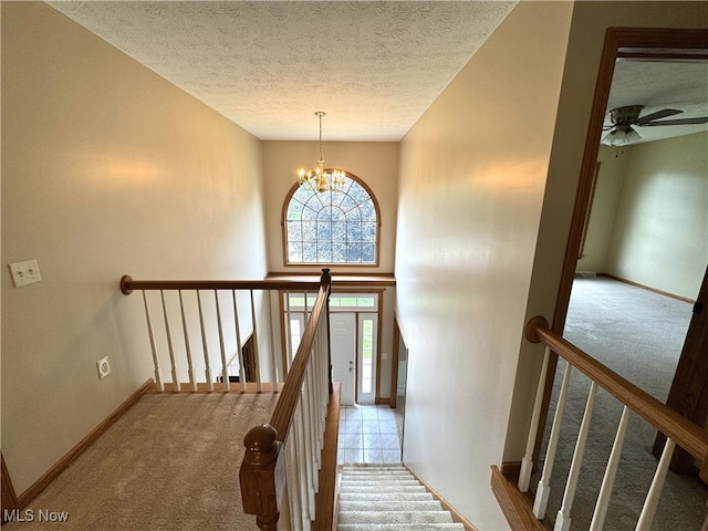 2761 Timberline Dr, Cortland, OH 44410 - stairway featuring a textured ceiling, carpet floors, baseboards, and a chandelier