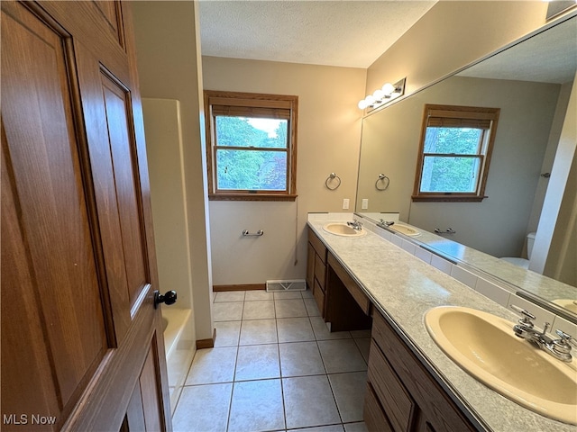 2761 Timberline Dr, Cortland, OH 44410 - bathroom featuring double vanity, toilet, baseboards, a textured ceiling, and a bathtub