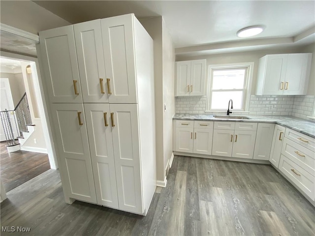 4485 Baintree Rd, University Heights, OH 44118 - kitchen featuring a sink, wood finished floors, decorative backsplash, and white cabinetry
