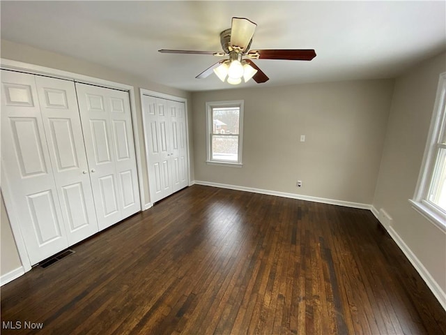 4485 Baintree Rd, University Heights, OH 44118 - unfurnished bedroom featuring multiple closets, dark wood-type flooring, baseboards, and ceiling fan