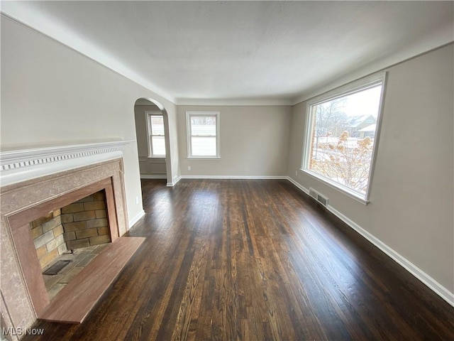 4485 Baintree Rd, University Heights, OH 44118 - unfurnished living room with dark wood-style flooring, arched walkways, baseboards, and a fireplace with flush hearth
