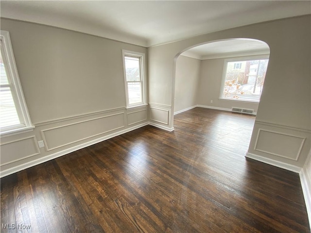4485 Baintree Rd, University Heights, OH 44118 - spare room with plenty of natural light, arched walkways, dark wood-type flooring, a decorative wall, and a wainscoted wall