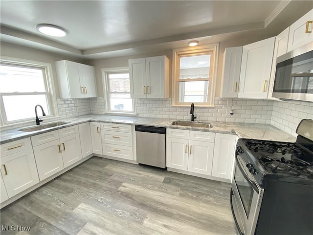 4485 Baintree Rd, University Heights, OH 44118 - kitchen featuring appliances with stainless steel finishes, a sink, light wood finished floors, and white cabinets