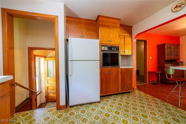 18288 Township Rd Unit 284, Coshocton, OH 43812 - kitchen featuring freestanding refrigerator, oven, brown cabinets, arched walkways, and light countertops
