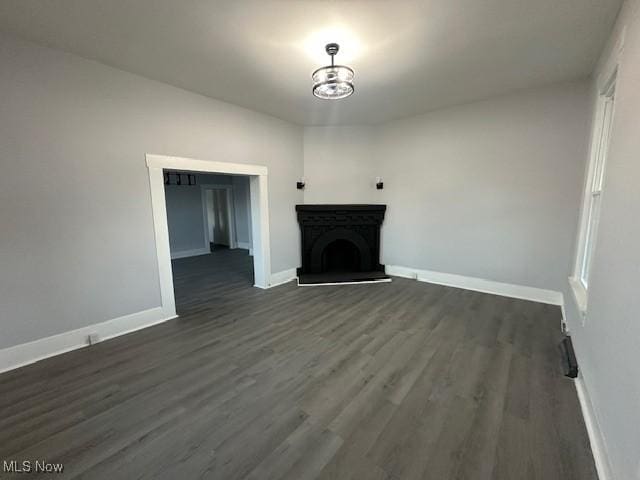 1264 Linden Ave, Zanesville, OH 43701 - unfurnished living room with dark wood-type flooring, baseboards, a fireplace with raised hearth, and a chandelier