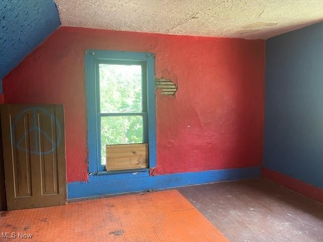 532 4th St SW, Massillon, OH 44647 - additional living space featuring a textured ceiling, vaulted ceiling, and a textured wall