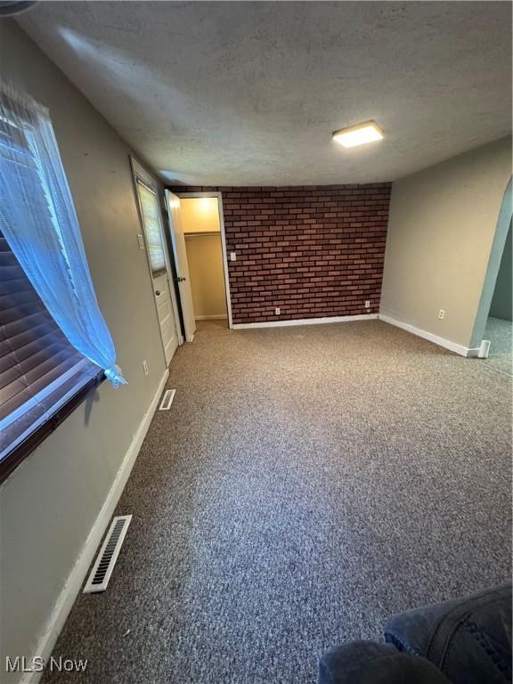 4940 State Route 26, Marietta, OH 45750 - unfurnished living room with brick wall, baseboards, carpet floors, and a textured ceiling