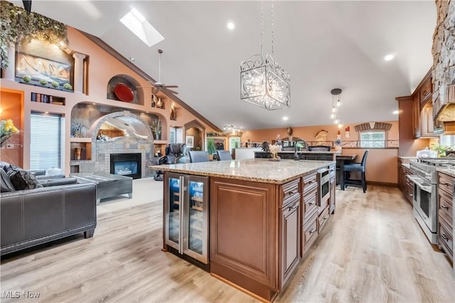 13817 Lakewood Heights Blvd, Lakewood, OH 44107 - kitchen with beverage cooler, range with two ovens, a glass covered fireplace, brown cabinetry, and a skylight