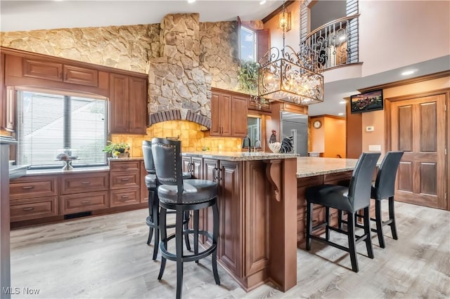 13817 Lakewood Heights Blvd, Lakewood, OH 44107 - kitchen with stainless steel built in refrigerator, light wood-style flooring, high vaulted ceiling, a breakfast bar area, and an island with sink