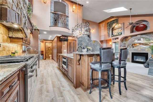 13817 Lakewood Heights Blvd, Lakewood, OH 44107 - kitchen with stainless steel appliances, a skylight, decorative backsplash, a towering ceiling, and light wood-style flooring