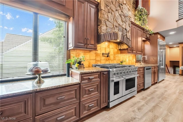 13817 Lakewood Heights Blvd, Lakewood, OH 44107 - kitchen with premium appliances, backsplash, light wood-style floors, light stone counters, and a sink