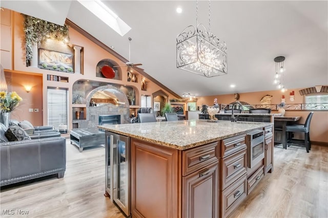 13817 Lakewood Heights Blvd, Lakewood, OH 44107 - kitchen featuring wine cooler, open floor plan, a skylight, brown cabinetry, and light stone counters