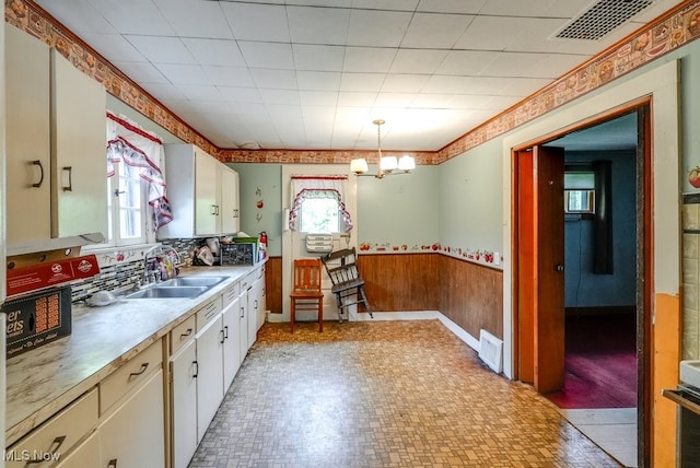 14721 Zenith Dr, Newbury, OH 44065 - kitchen with a sink, a wainscoted wall, light countertops, white cabinetry, and hanging light fixtures