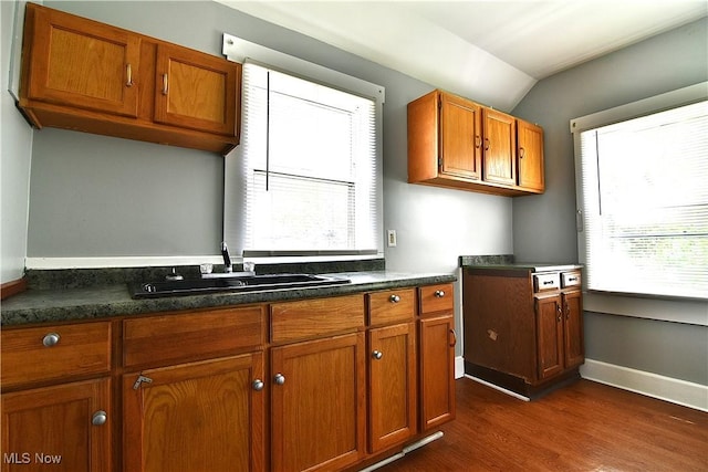 1033 Monnot Pl NW, Canton, OH 44703 - kitchen with a sink, dark wood-type flooring, brown cabinetry, dark countertops, and vaulted ceiling