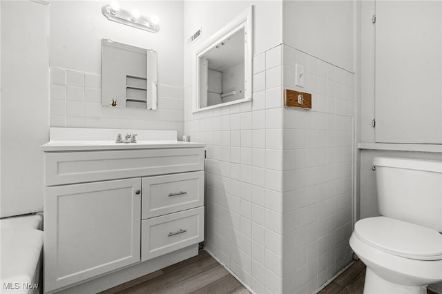 1023 Fulton Rd NW, Canton, OH 44703 - bathroom featuring tile walls, wood finished floors, vanity, toilet, and wainscoting