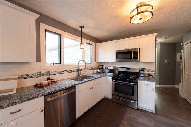 10957 Mogadore Ave NW, Uniontown, OH 44685 - kitchen with stainless steel appliances, a sink, a textured ceiling, white cabinetry, and backsplash