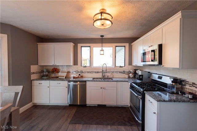 10957 Mogadore Ave NW, Uniontown, OH 44685 - kitchen with appliances with stainless steel finishes, a sink, dark wood-style flooring, backsplash, and a textured ceiling