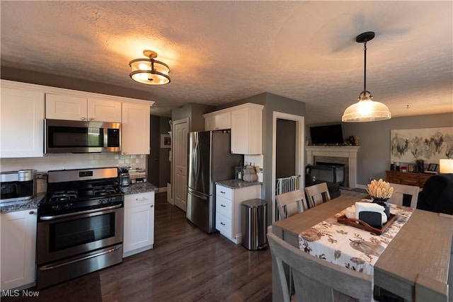 10957 Mogadore Ave NW, Uniontown, OH 44685 - kitchen with appliances with stainless steel finishes, white cabinetry, dark wood-style flooring, backsplash, and dark stone counters